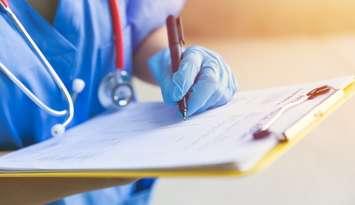 Nurse writing on clipboard