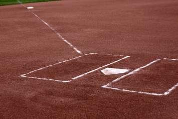 A close-up of the batters boxes and home plate on a vacant baseball diamond. © Can Stock Photo / ca2hill