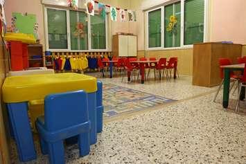 Interiors of a nursery class with coloredchairs and drawings of children hanging on the walls. © Can Stock Photo / ChiccoDodiFC