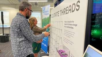  Launch event guests share their thoughts on an interactive “Climate Threads” exhibit, helping visualize the impact of climate change on our communities. Photo from the Nuclear Innovation Institute.