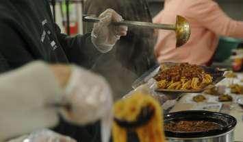 People prepare plates of spaghetti at a Salvation Army soup kitchen. Feb. 25, 2014. (Photo by Levin Boland)