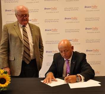 Patrick Dillon (standing), Business Manager and Secretary Treasurer of the Provincial Building and Construction Trades Council of Ontario, and Duncan Hawthorne, Bruce Power President and CEO sign the collaboration agreement Wednesday during a ceremony in Hamilton.  
Photo submitted