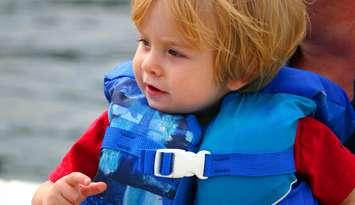 Close-up of a young boy in a life jacket on a boat. © Can Stock Photo / soupstock