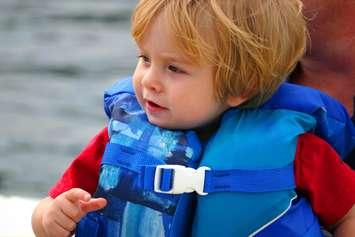 Close-up of a young boy in a life jacket on a boat. © Can Stock Photo / soupstock