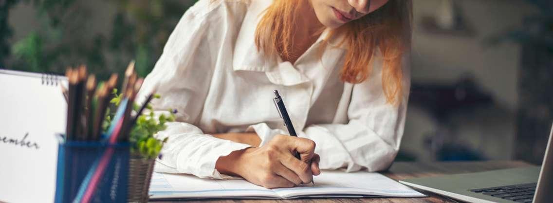 A woman writing into a book. File photo from Pra-chid/iStock / Getty Images Plus.