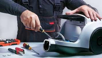 A person repairing a vacuum cleaner. (Photo courtesy of Sergei Chuyko/iStock/Getty Images Plus via Getty Images)