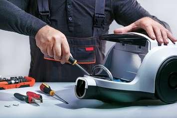 A person repairing a vacuum cleaner. (Photo courtesy of Sergei Chuyko/iStock/Getty Images Plus via Getty Images)