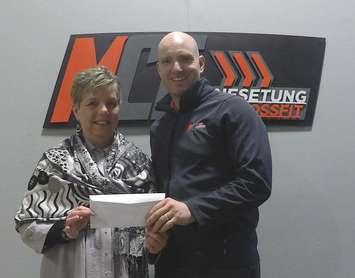 Huron Women’s Shelter Executive Director Michele Hansen accepts a  cheque for $840 from Owner and Head Trainer of Menesetung CrossFit Chris Watson. The money was raised during the Air Squat Intramural Challenge. Photo submitted  by Heather Boa.

recently.