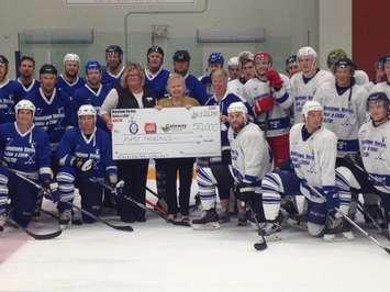 Anne Marie Thomson, Huron-Goderich Strong Kids Campaign, Karen Davis, President and CEO of Alexandra Marine General Hospital and Sheila Schuehlien, Gateway Rural Health Institute in Seaforth, hold a cheque for $50,000 that was raised during the Raise A Little Health Hockey Game in Goderich. They are surrounded by the players who participated. (Photo by Steve Sabourin)
