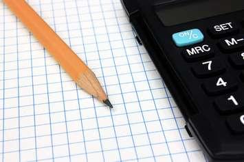 Black calculator and pencil on graph paper. © Can Stock Photo / berczy04