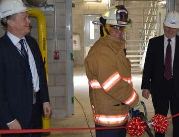 President & CEO Duncan Hawthorne [center] uses the jaws of life to cut
the ribbon on Bruce Power's new fire training facility. Photo by Jordan MacKinnon.