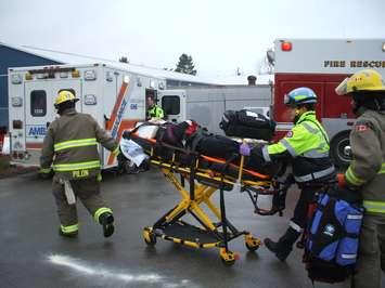 Firefighters and EMS staff roll a stretcher to a waiting ambulance in a mock scenario.
(Photo: James Armstrong)