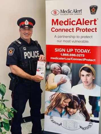 Cst. Rodney Hilton of the West Grey Police Service next to a MedicAlert information banner. (Photo submitted by Cst. Cory Trainor, West Grey Police Service Media Relations Officer)