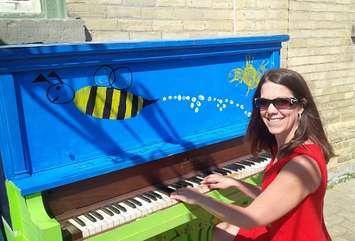 Angela Smith checks out the piano in the laneway parkette beside the town hall in Clinton. (photo by Bob Montgomery)