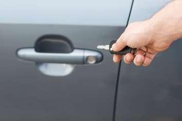 Person using key to lock a car door. © Can Stock Photo / dolgachov